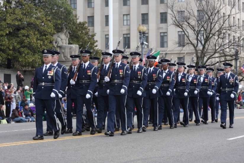 A group of service members march down a street.