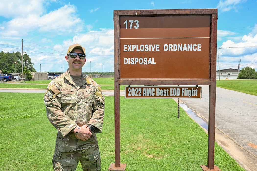 A man in uniform stands next to a sign.