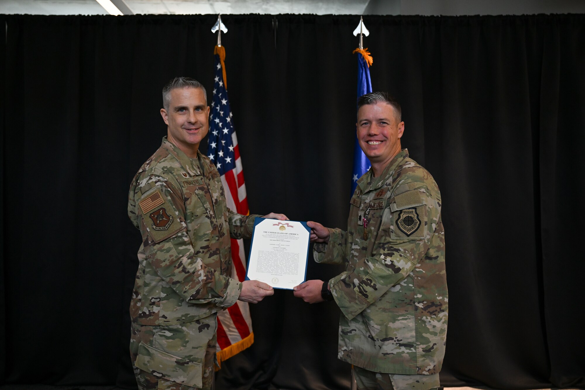 U.S. Air Force Col. Andrew Finkler, 850th Spectrum Warfare Group commander, left, presents U.S. Air Force Lt. Col. Charles Friesz, 563d Electronic Warfare Squadron outgoing commander, right, with a Meritorious Service Medal for his leadership as the unit commander during a change of command ceremony in San Antonio, Texas, June 30, 2025. Friesz served as the unit’s first commander after reactivating it to serve as the 350th Spectrum Warfare Wing’s software development squadron in 2024. (U.S. Air Force photo by Capt. Benjamin Aronson)