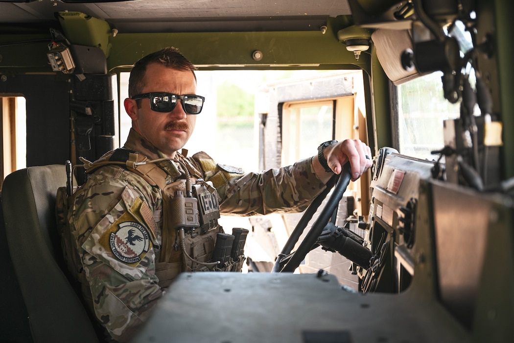 A man in uniform sits in a military vehicle.