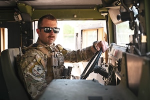 A man in uniform sits in a military vehicle.