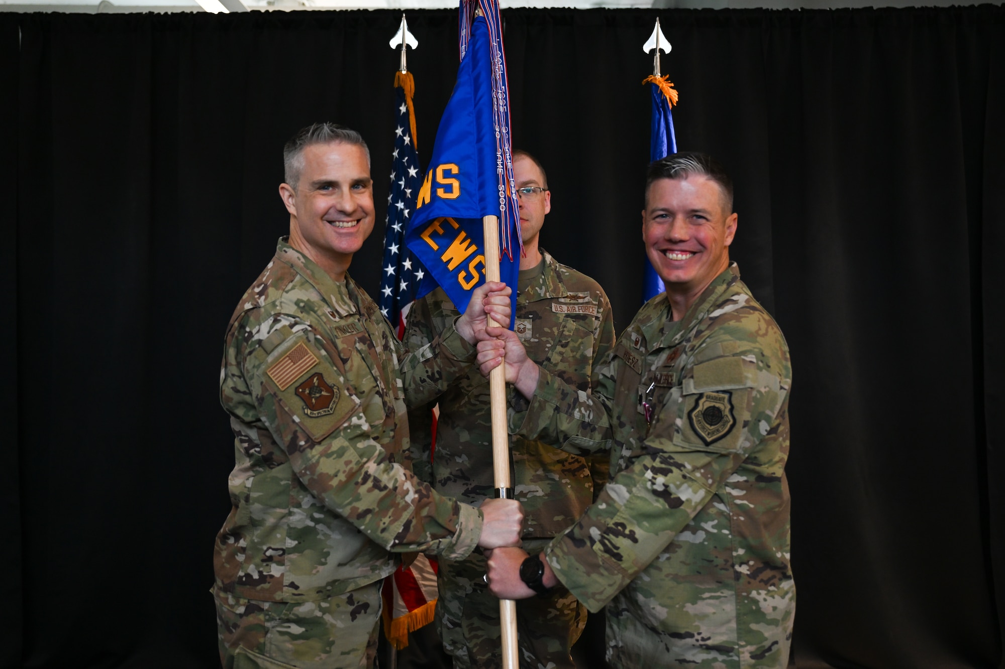 U.S. Air Force Col. Andrew Finkler, 850th Spectrum Warfare Group commander, left, takes the unit guidon back from U.S. Air Force Lt. Col. Charles Friesz, 563d Electronic Warfare Squadron outgoing commander, right, during a change of command ceremony in San Antonio, Texas, June 30, 2025. Friesz served as the unit’s first commander after reactivating it to serve as the 350th Spectrum Warfare Wing’s software development squadron in 2024. (U.S. Air Force photo by Capt. Benjamin Aronson)