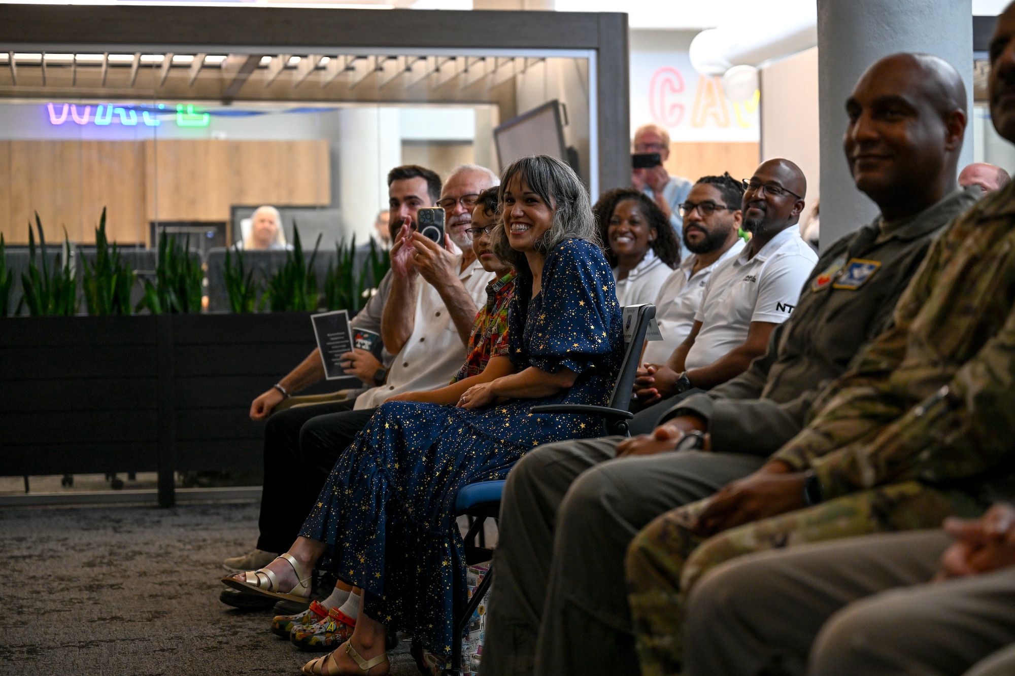 Audience members listen to a speech by U.S. Air Force Lt. Col. Adrian De Freitas, 563d Electronic Warfare Squadron commander, after he took command during a change of command ceremony in San Antonio, Texas, June 30, 2025. The 563 EWS serves as a software development training arm, enabling others with best practices and techniques to secure electromagnetic spectrum superiority (U.S. Air Force photo by Capt. Benjamin Aronson)