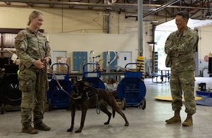 U.S. Air Force Staff Sgt. Alexis Krippel, left, smiles while speaking with Col. Jun S. Oh during a recognition visit at Joint Base Andrews, Maryland, on June 16, 2025. Both are in uniform, standing outdoors in a casual, friendly exchange. Oh recognized Krippel for her exceptional performance as a military working dog handler.