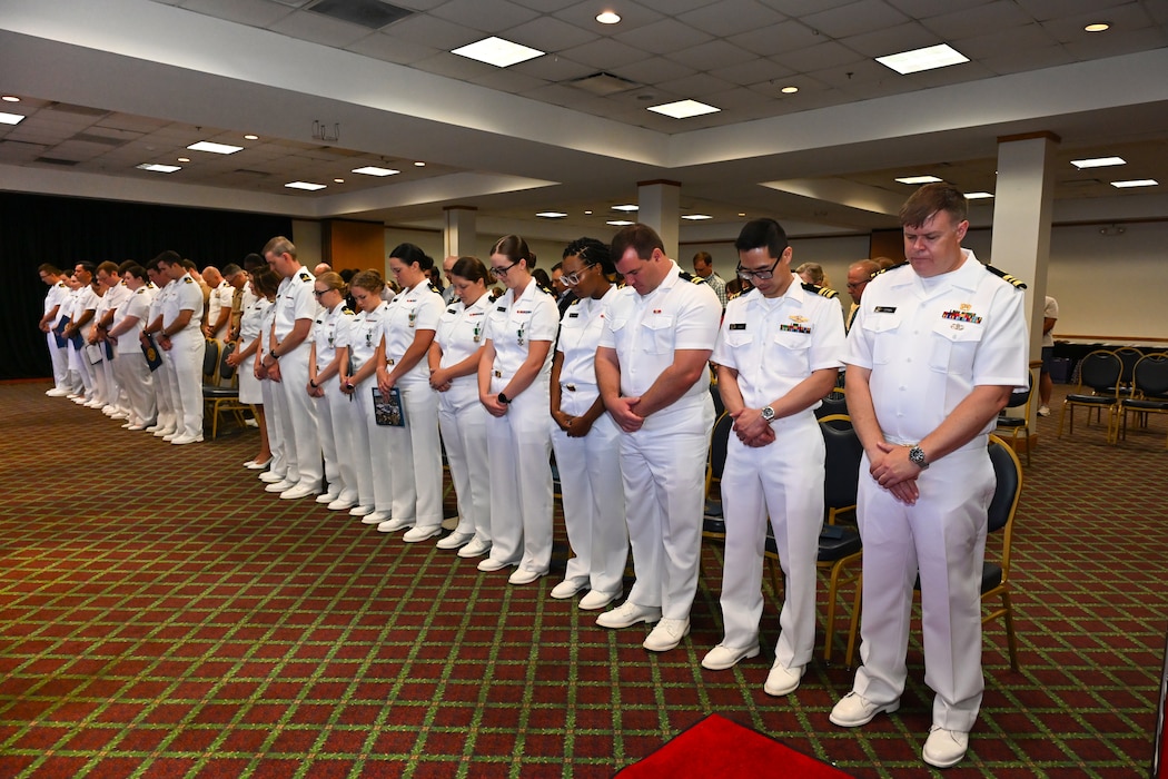 250630-N-FM959-2289 Jacksonville, FL. (June 30, 2025) Naval Hospital Jacksonville Family Medicine residents and interns bow their head during the benediction at their graduation ceremony, held June 30, onboard Naval Air Station Jacksonville. (U.S. Navy photo by Michael Campbell)