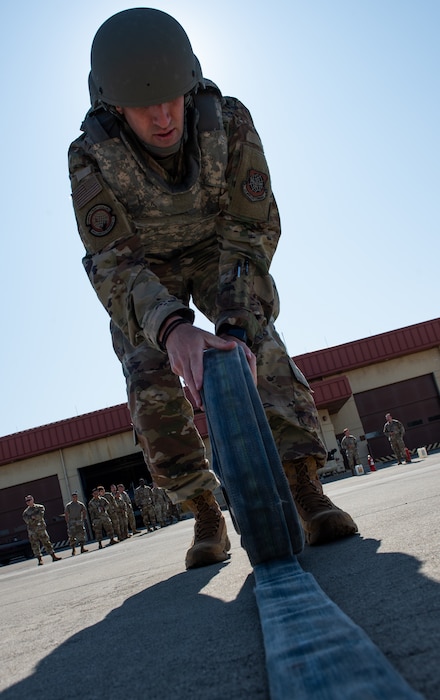 Airman rolls a hose