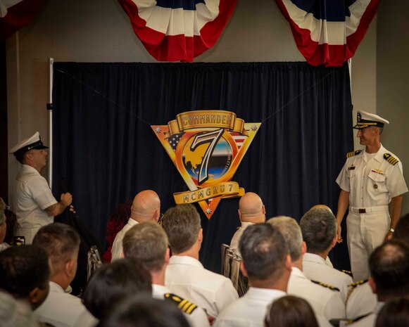 Capt. Peter W. Haynes, Commander, Mine Countermeasures Group (MCMGRU) 7, unveils the command logo of MCMGRU 7 during a change of command and Commander, Task Force (CTF) 77 establishment ceremony in Sasebo, Japan June 26, 2025.