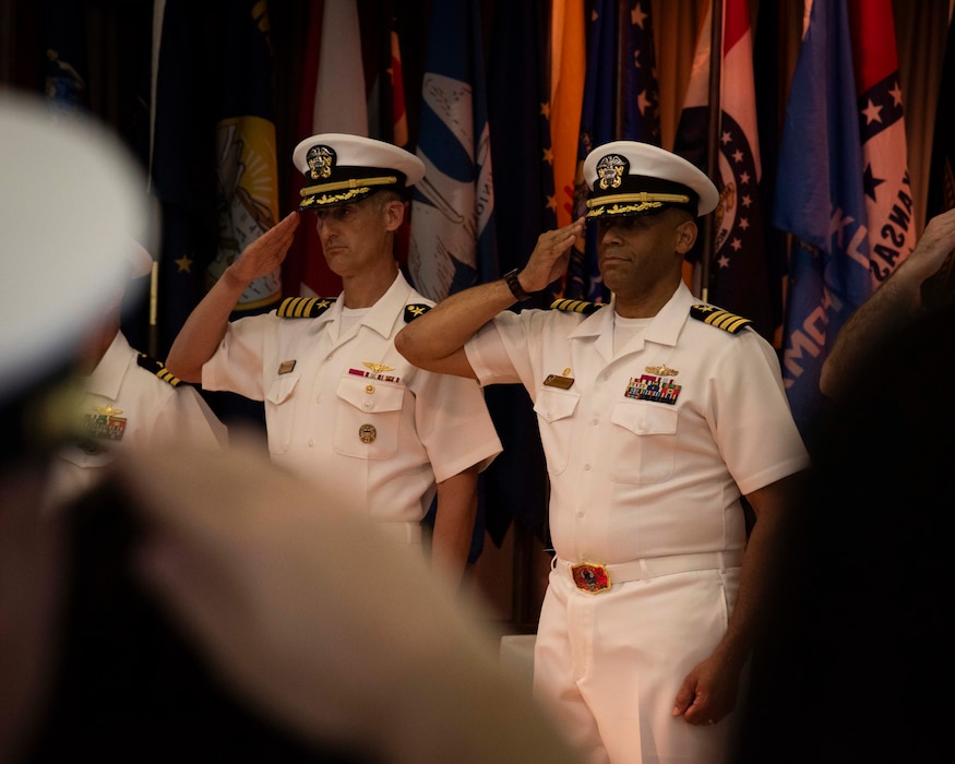 Capt. Antonio L. Hyde, the commodore of Mine Countermeasures Squadron (MCMRON) 7, and Capt. Peter W. Haynes, deputy commodore, salute the United States and Japan flags during a change of command and Commander, Task Force (CTF) 77 establishment ceremony in Sasebo, Japan June 26, 2025.