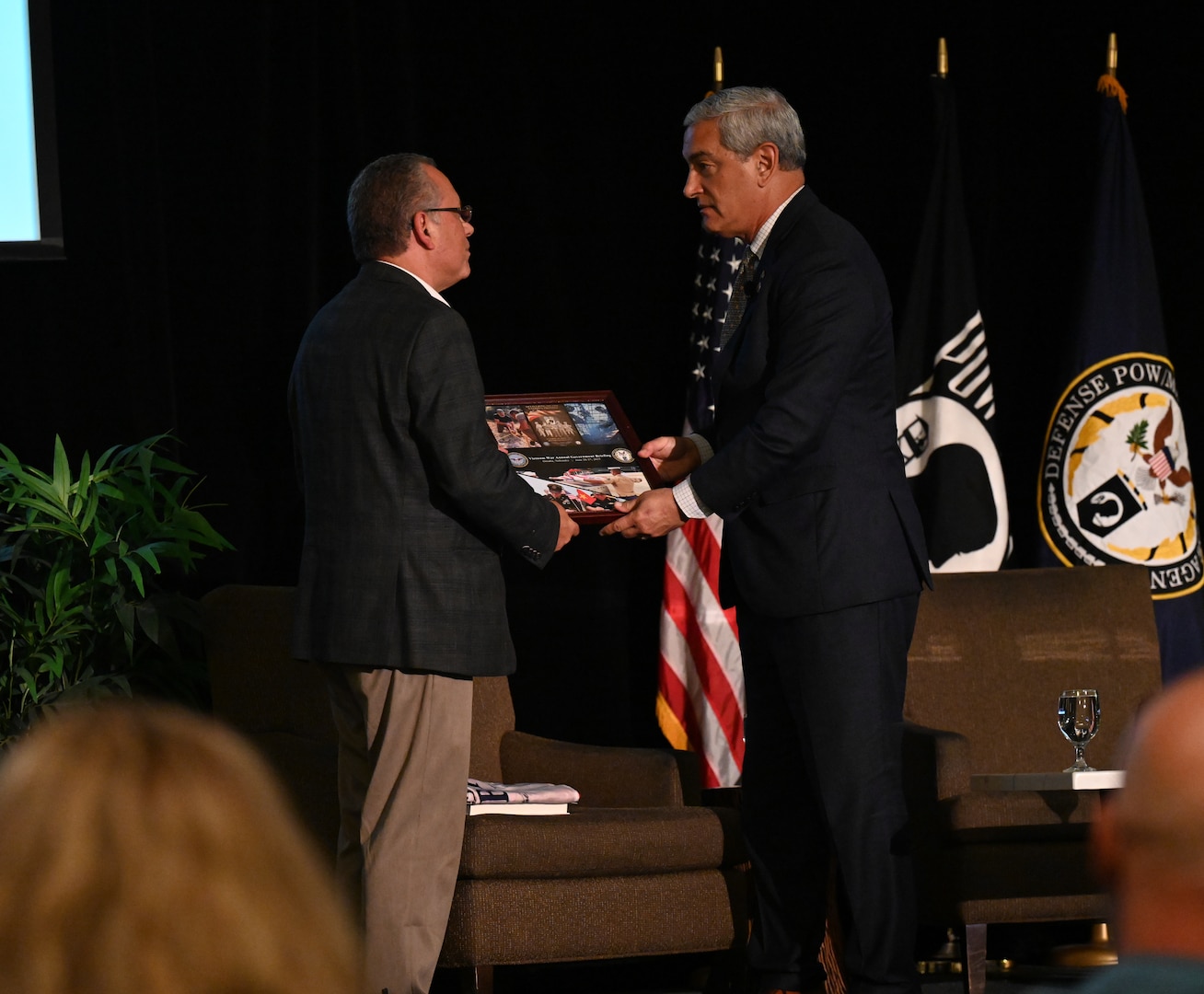 Kelly McKeague, Defense POW/MIA Accounting Agency director, presents a collage of appreciation to George Lutz, executive director of Honor and Remember, at the Vietnam War Annual Government Briefing, Omaha, Nebraska, June 26, 2025.