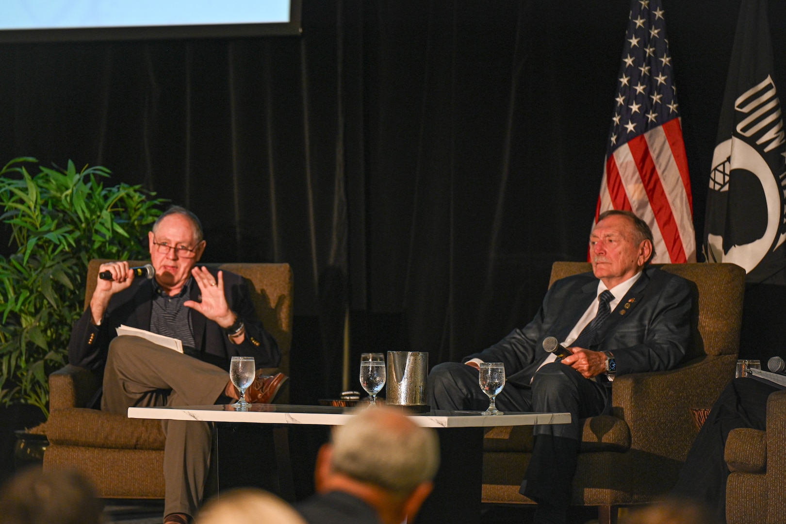 Retired U.S. Navy Capt. Ned Lundquist, left, and Johnnie Webb, Vietnam War veteran and former Defense POW/MIA Accounting Agency Outreach and Communications deputy director, right, give a brief at the Vietnam War Annual Government Briefing, Omaha, Nebraska, June 26, 2025.