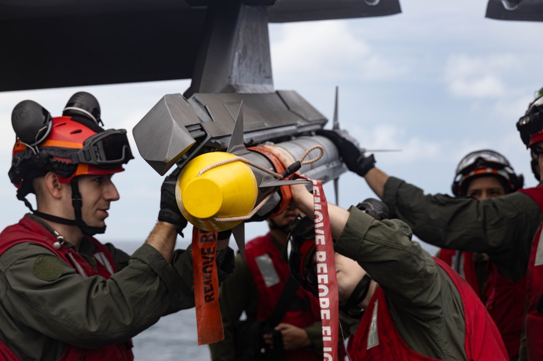 U.S. Marines with Marine Fighter Attack Squadron (VMFA) 242, 31st Marine Expeditionary Unit, attach an AIM-9X-2 missile to a U.S. Marine Corps F-35B Lightning II aircraft assigned to VMFA 242 during an ordnance load aboard the amphibious assault ship USS America, in the Coral Sea, June 29, 2025. Marines with VMFA 242 arm F-35Bs with multi-discipline strike capabilities to support combined-joint all domain operations in key maritime terrain. The 31st MEU is operating aboard ships of the USS America Amphibious Ready Group in the 7th Fleet area of operations, the U.S. Navy’s largest forward-deployed numbered fleet, and routinely interacts and operates with allies and partners in preserving a free and open Indo-Pacific region. (U.S. Marine Corps photo by Sgt. Peter Rawlins)