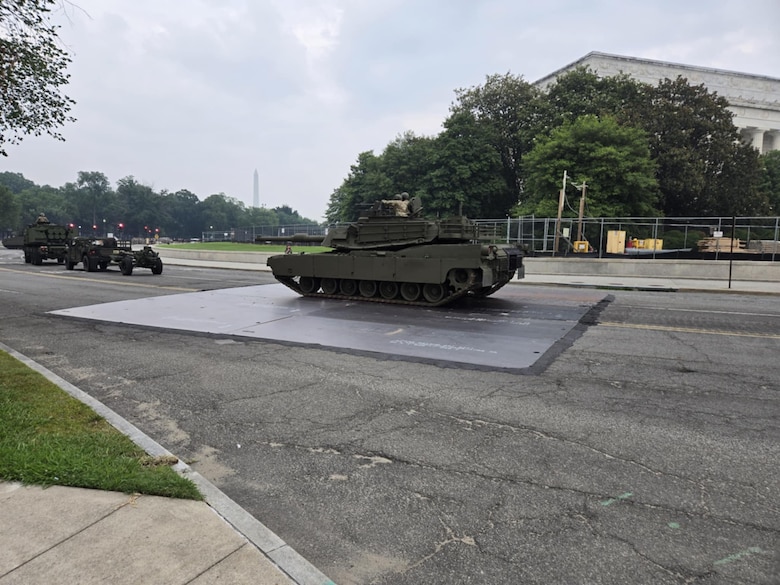 A tank rests on top of a large steel plate in the middle of a roadway.