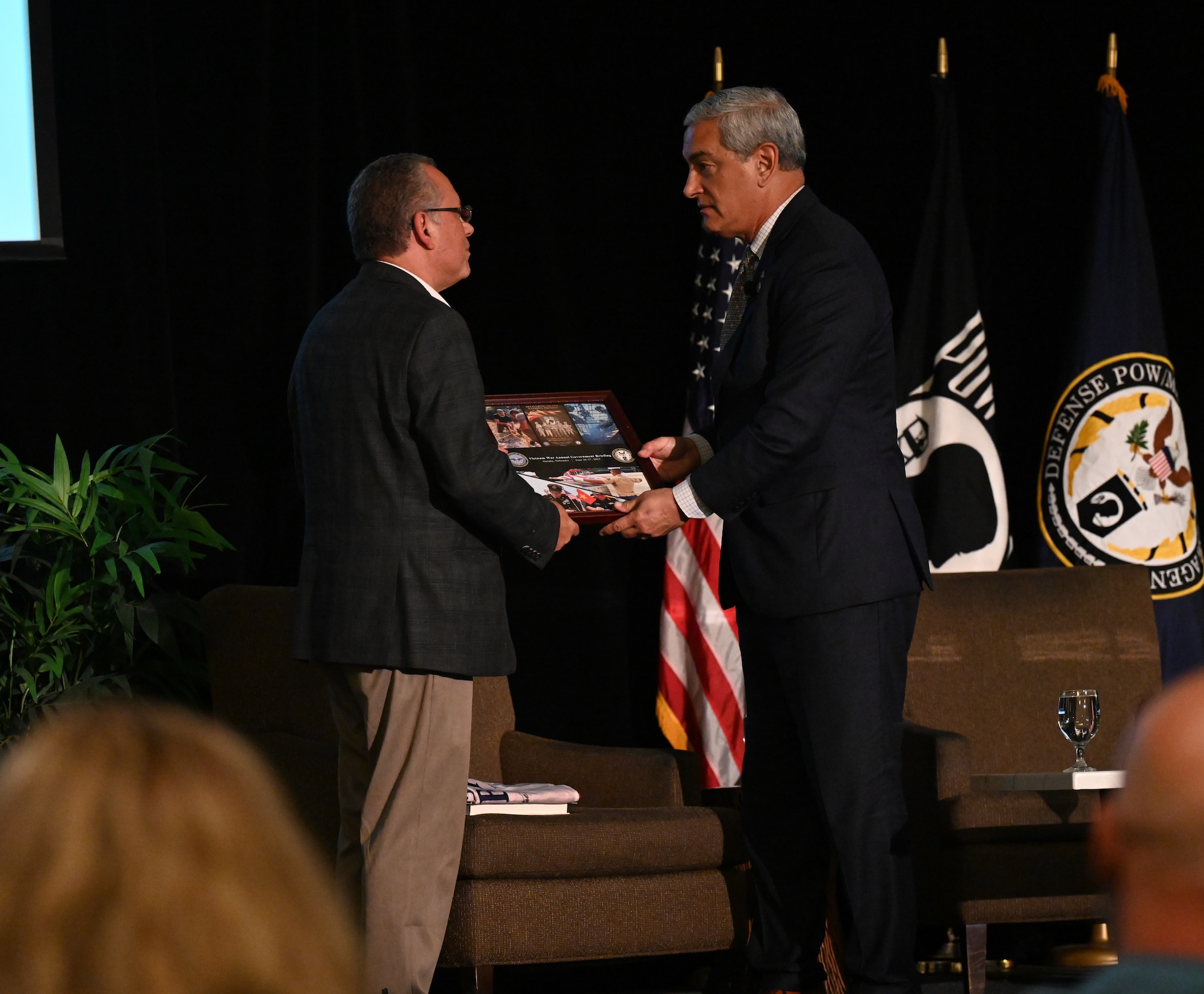 Kelly McKeague, Defense POW/MIA Accounting Agency director, presents a collage of appreciation to George Lutz, executive director of Honor and Remember, at the Vietnam War Annual Government Briefing, Omaha, Nebraska, June 26, 2025.