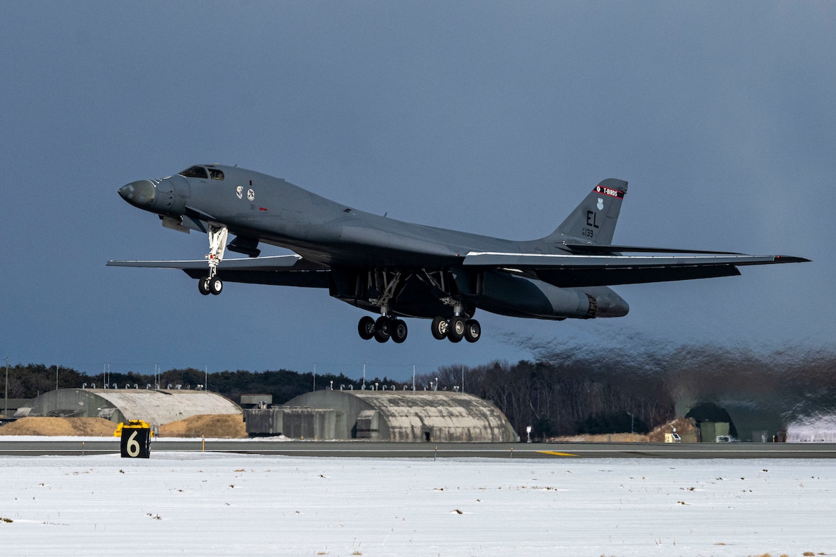 A long pointy plane with long, thin wings, lands on a snowy air strip.