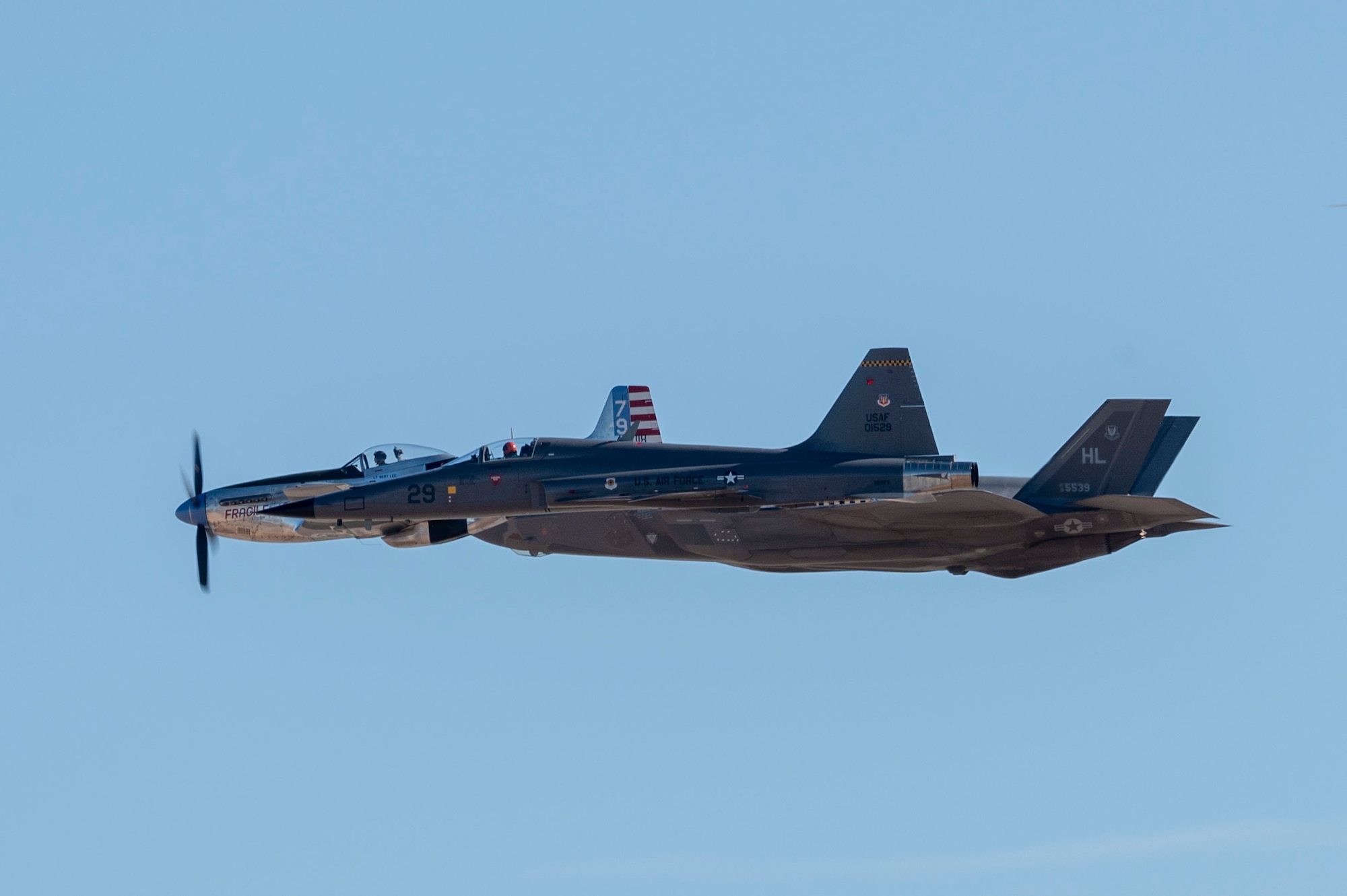 A P-51 Mustang aircraft, F-5 Northrop aircraft and F-22 Raptor aircraft maneuver in tight formation at Davis-Monthan Air Force Base, Arizona, Mar. 1, 2025. The aircraft flew during the Heritage Flight Training Course, where aircrew practice ground and flight training to enable civilian pilots of historic military aircraft and U.S. Air Force pilots of current fighter aircraft to fly safely in formations together. (U.S. Air Force photo by Airman Samantha Melecio)