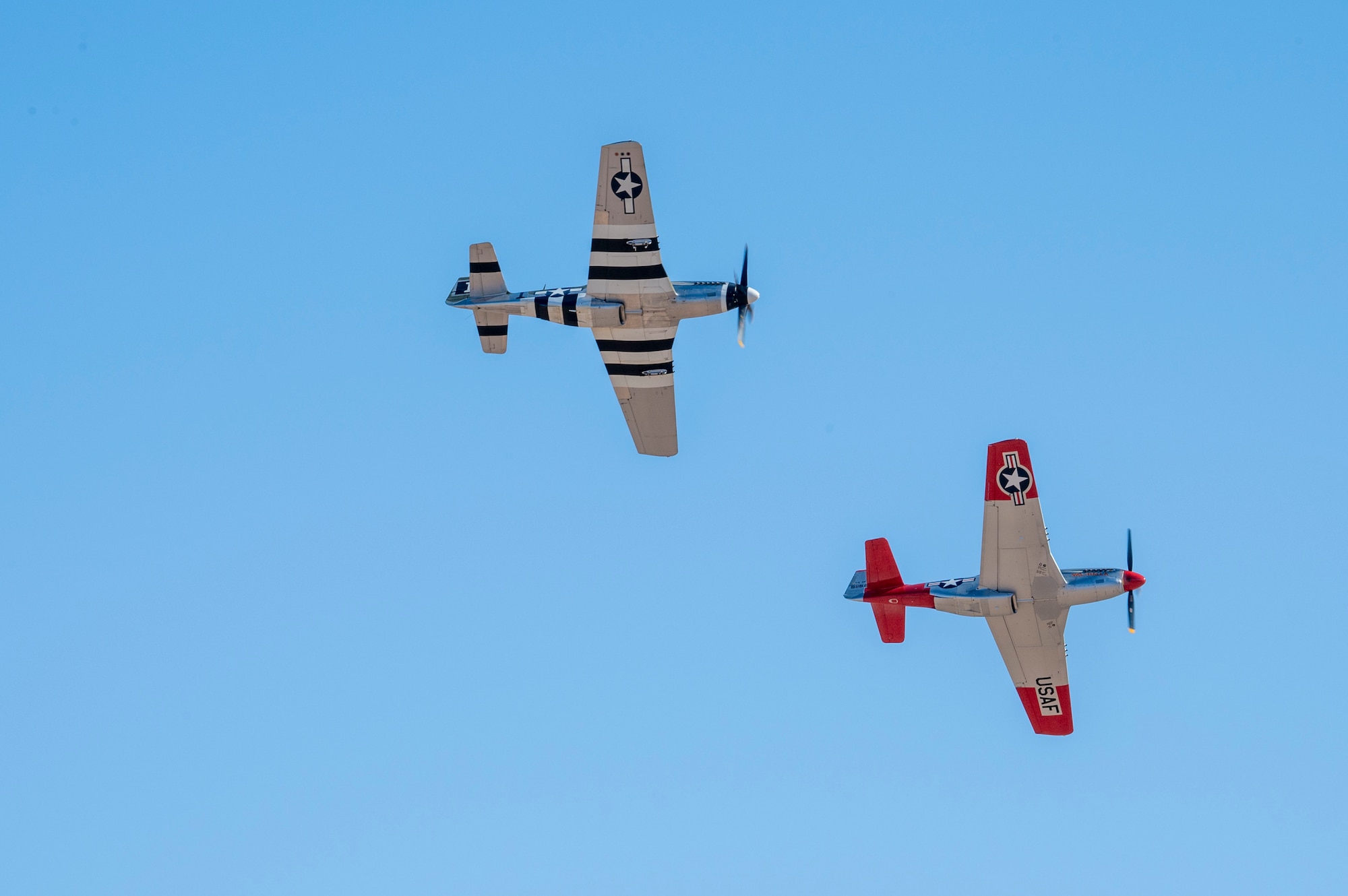 Two P-51 Mustang aircraft fly in formation during the Heritage Flight Training Course at Davis-Monthan Air Force Base, Arizona, Mar. 1, 2025. The P-51 was an American long-range fighter-bomber airframe used during World War II and the Korean War. (U.S. Air Force photo by Airman Samantha Melecio)