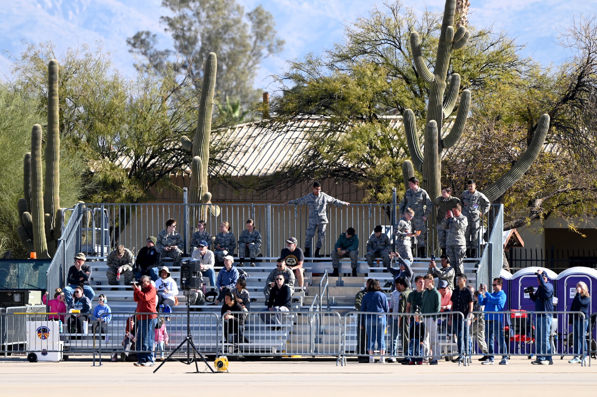 Crowd members watch aircraft perform aerial maneuvers  during the Heritage Flight Training Course at Davis-Monthan Air Force Base, Arizona, March 1, 2025. Demo teams dedicated their last flight of the day to past and present members of the U.S. Armed Forces. (U.S. Air Force photo by Senior Airman Andrew Garavito)