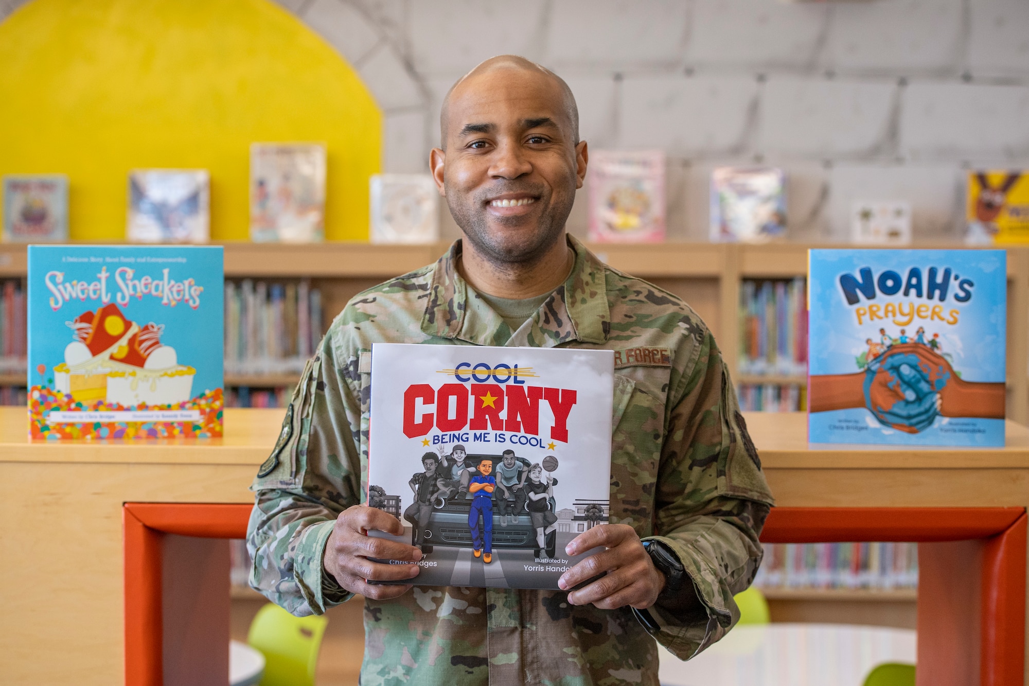 U.S. Air Force Maj. Christopher Bridges, the 732nd Airlift Squadron executive officer, 514th Air Mobility Wing, displays children's books he has published at the Joint Base McGuire-Dix-Lakehurst Library, March 1, 2025.