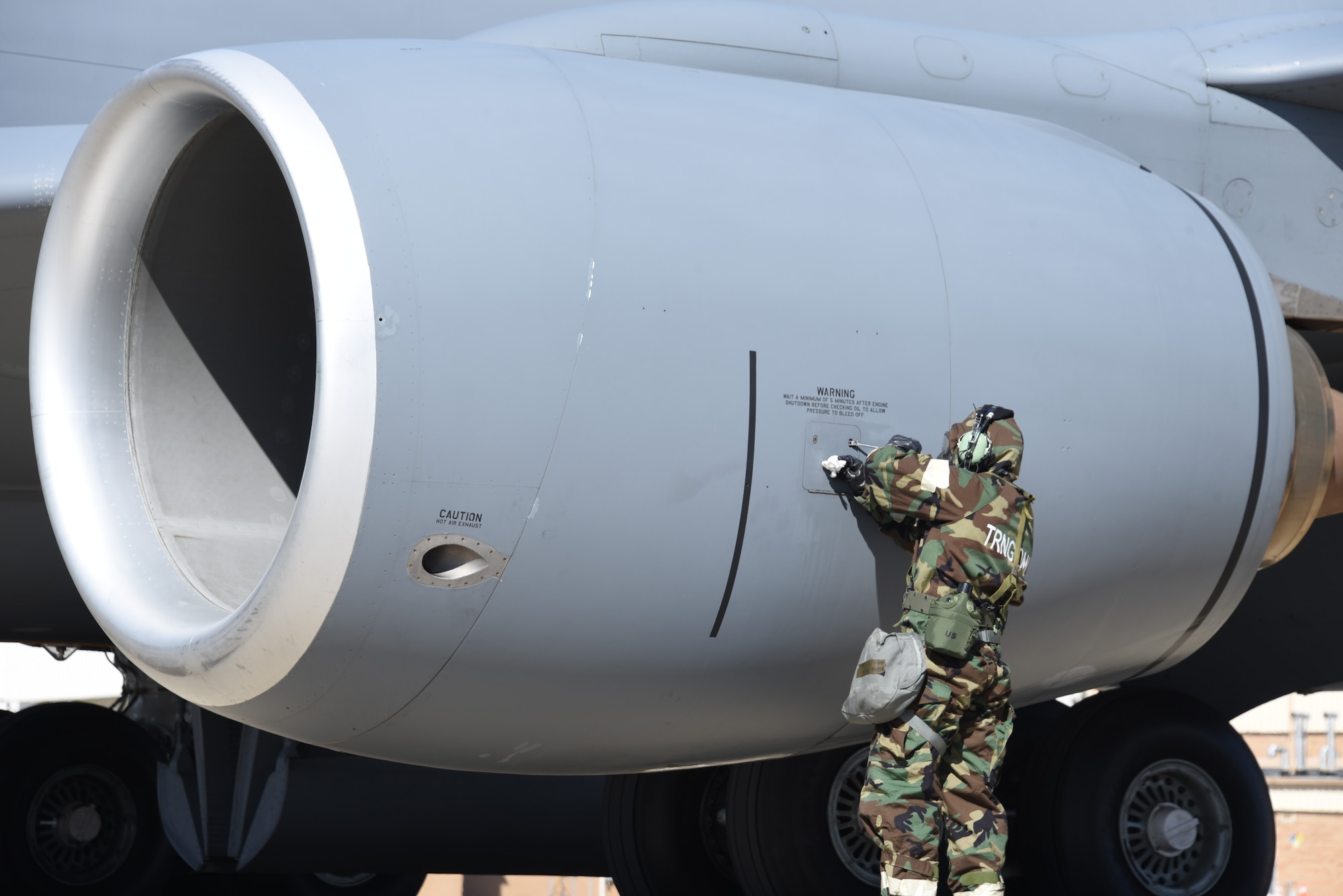 A U.S. Air National Guard Airman of the 185th Air Refueling Wing refastens a cover after checking the oil of a U.S. Air Force KC-135 Stratotanker of the 185th Air Refueling Wing while wearing Mission-Oriented Protective Postures gear during a training event at the 185th Air Refueling Wing in Sioux City, Iowa, March 1, 2025.