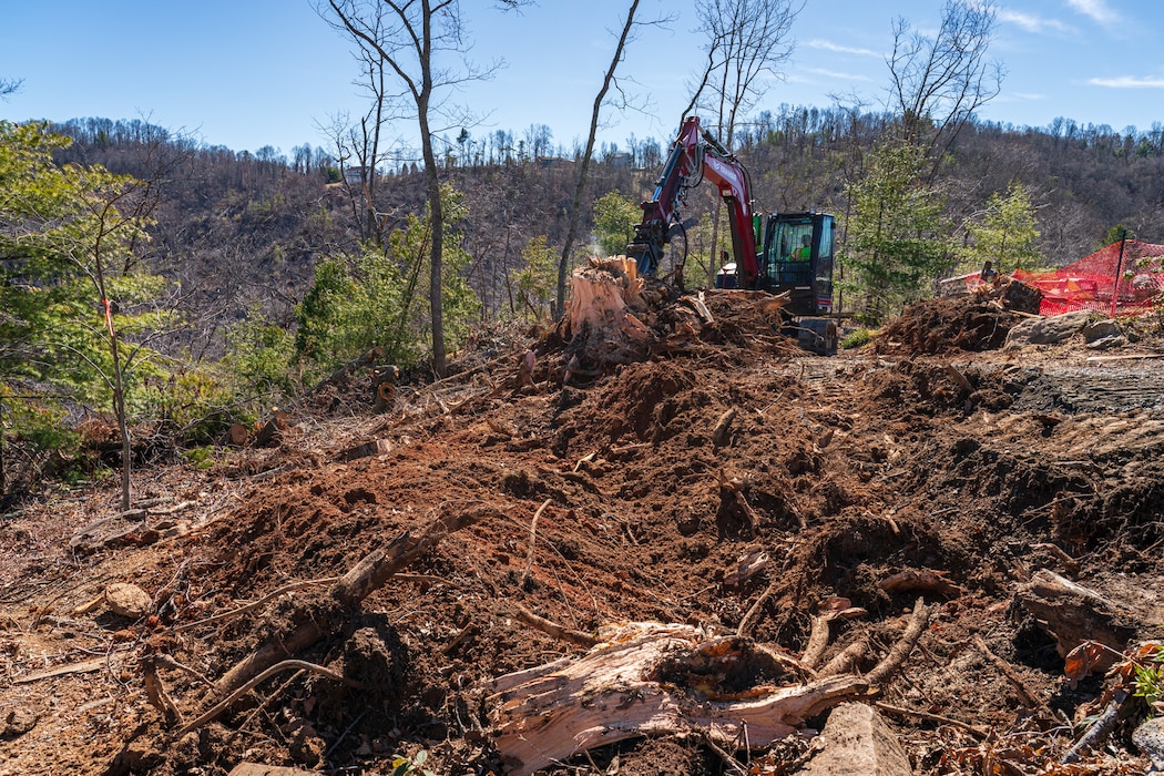 Large tractor scooping dirt on a mountain.