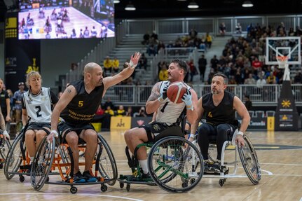 Carlos Valerio, center left, plays defense during a wheelchair basketball match vs. New Zealand at the 2025 Invictus Games, held Feb. 8-16 in Vancouver and Whistler, Canada. As a member of Team U.S. for the second time, Valerio – a Navy veteran, Army civilian employee and gastric cancer survivor – competed in the biathlon and on a mixed-nation “Unconquered” team in basketball, earning a bronze medal. It was the first time an Unconquered team earned a medal at Invictus.