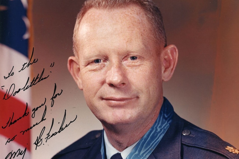 A man wearing a medal around his neck poses for a photo. An inscription is written on the side of the photo.