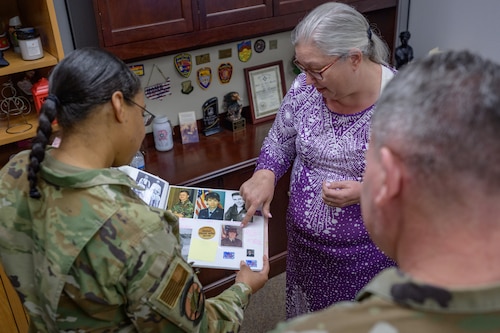 April Jones, 49th Contracting Squadron unit program coordinator, center, shares an album of her family military heritage with U.S. Air Force Chief Master Sgt. Jennifer Nalls, Air Force Installation Contracting Center chief enlisted manager and U.S. Air Force Brig. Gen. Lance French, AFICC commander at Holloman Air Force Base, New Mexico, Feb. 24, 2025.