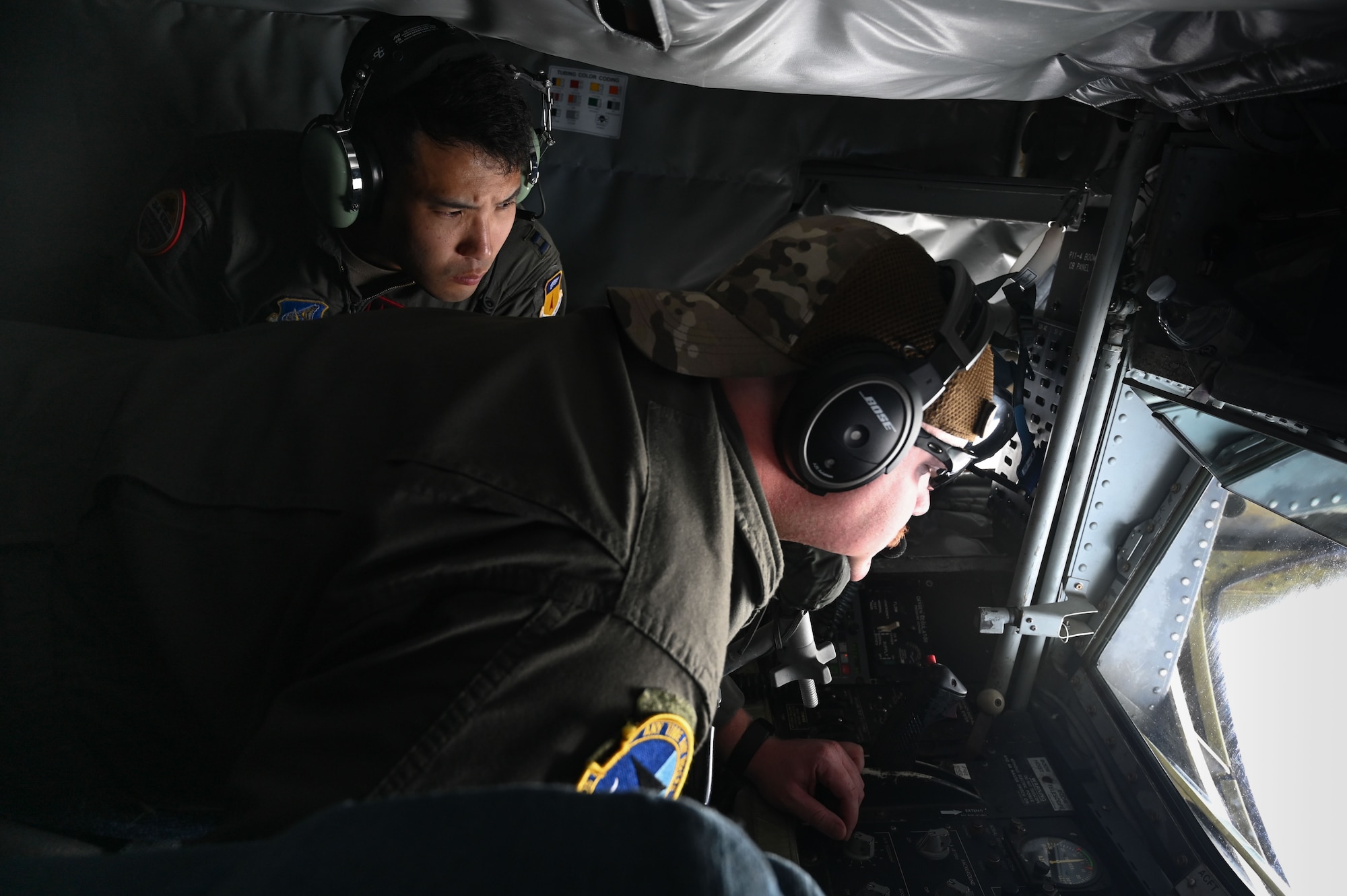 U.S. Air Force Capt. Maxwell Cheng, flight surgeon, 34th Expeditionary Bomb Squadron, observes Technical Sgt. Chris Kirk, boom operator, 506th Expeditionary Air Refueling Squadron, during a training mission over the Pacific Ocean, Feb. 26, 2025. Cheng assessed the physiological effects that the aircrew may experience on a typical refueling flight in order to better treat them post-flight. (U.S. Air Force photo by Airman 1st Class Natasha Ninete)