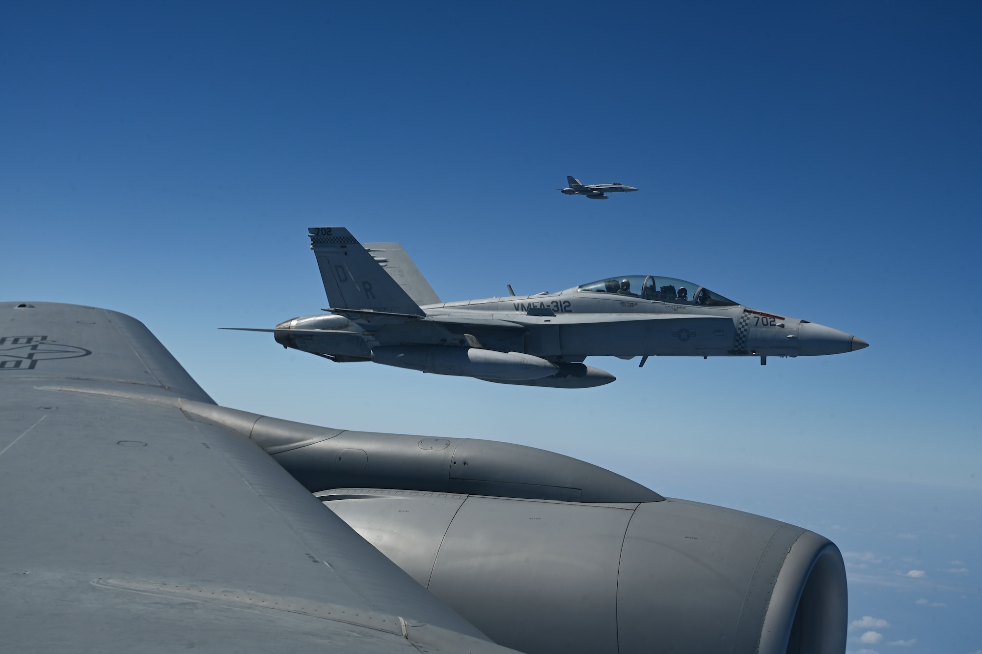 Two U.S. Marine Corps F/A-18C Hornets assigned to Marine Fighter Attack Squadron 312, Marine Corps Air Station, Iwakuni, Japan, fly alongside a U.S. Air Force KC-135 Stratotanker assigned to the 506th Expeditionary Air Refueling Squadron during a training mission over the Pacific Ocean, Feb. 26, 2025. The F/A-18Cs participated in a refueling mission led by the 506 EARS which originated from Andersen Air Force Base, Guam. (U.S. Air Force photo by Airman 1st Class Natasha Ninete)