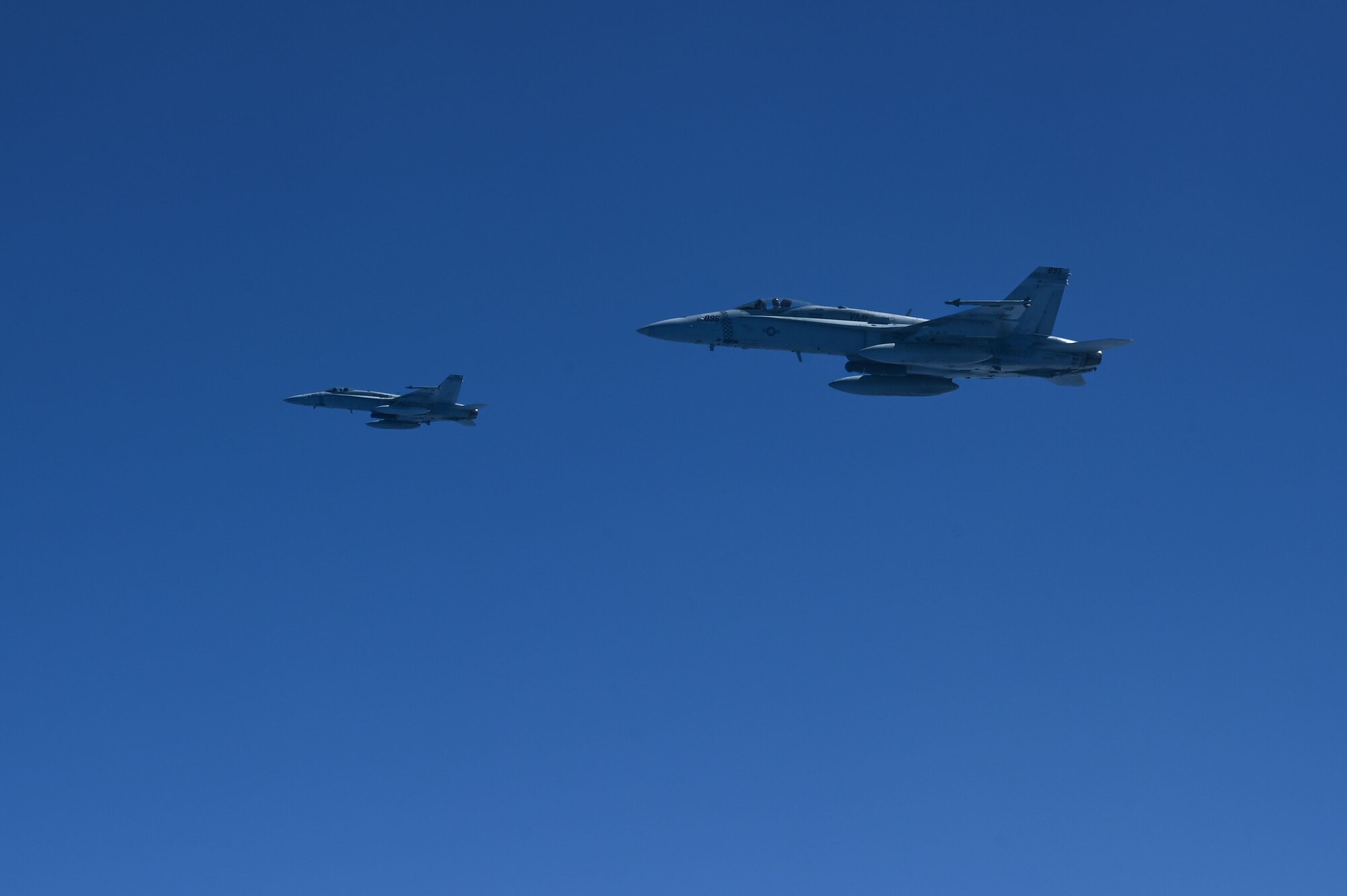 Two U.S. Marine Corps F/A-18C Hornets assigned to Marine Fighter Attack Squadron 312, Marine Corps Air Station, Iwakuni, Japan, fly side by side during a training exercise over the Pacific Ocean, Feb. 26, 2025. The F/A-18Cs participated in a refueling mission with the 506th Expeditionary Air Refueling Squadron which originated from Andersen Air Force Base, Guam. (U.S. Air Force photo by Airman 1st Class Natasha Ninete)