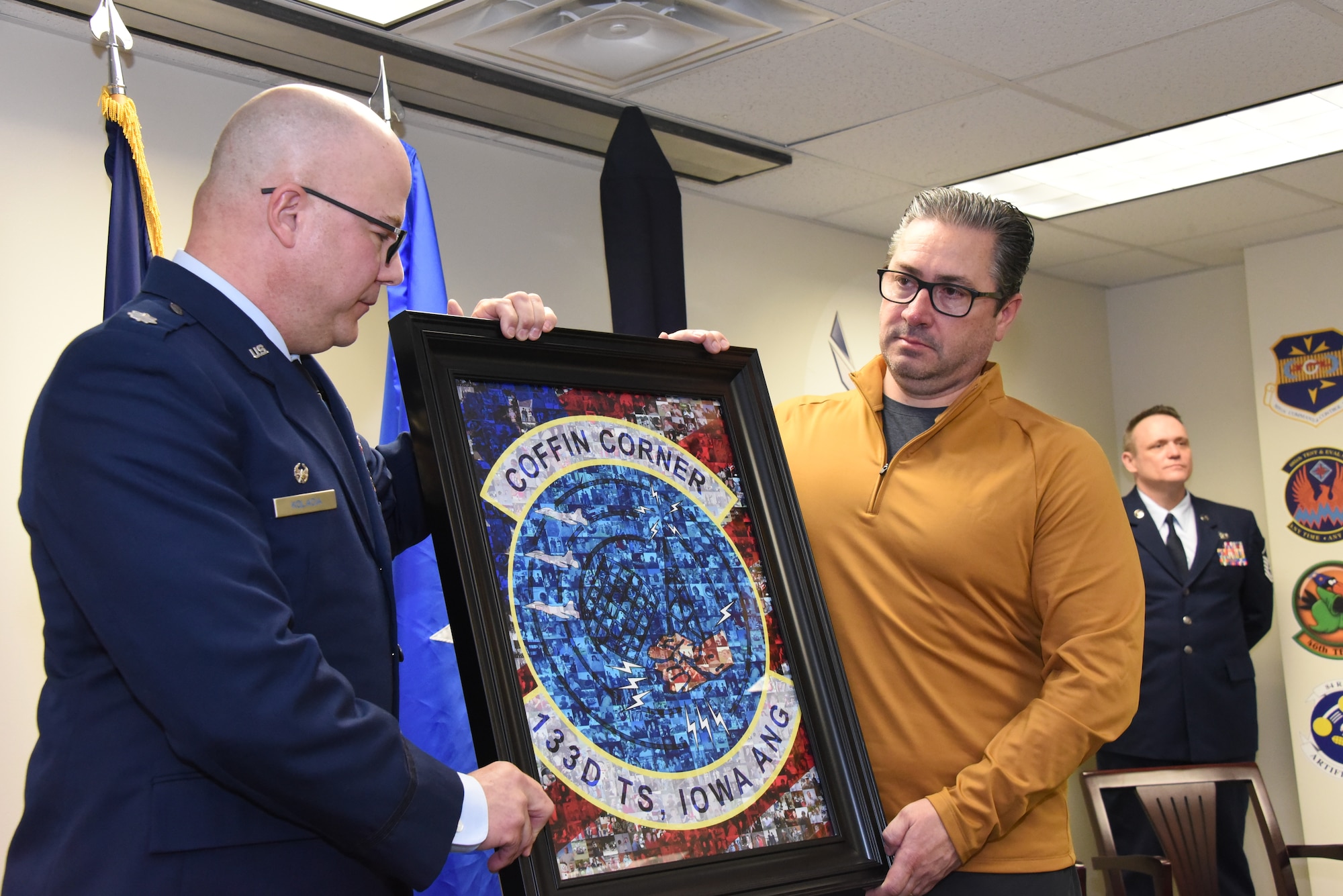 Lt. Col. Jason Kolacia, 133rd Test Squadron Commander, left, presents Matt Bemrich, Mayor of Fort Dodge, Iowa, right, with a gift, a framed insignia of the 133rd made of a collage of images