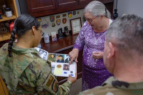 April Jones, 49th Contracting Squadron unit program coordinator, center, shares an album of her family military heritage with U.S. Air Force Chief Master Sgt. Jennifer Nalls, Air Force Installation Contracting Center chief enlisted manager and U.S. Air Force Brig. Gen. Lance French, AFICC commander at Holloman Air Force Base, New Mexico, Feb. 24, 2025.
