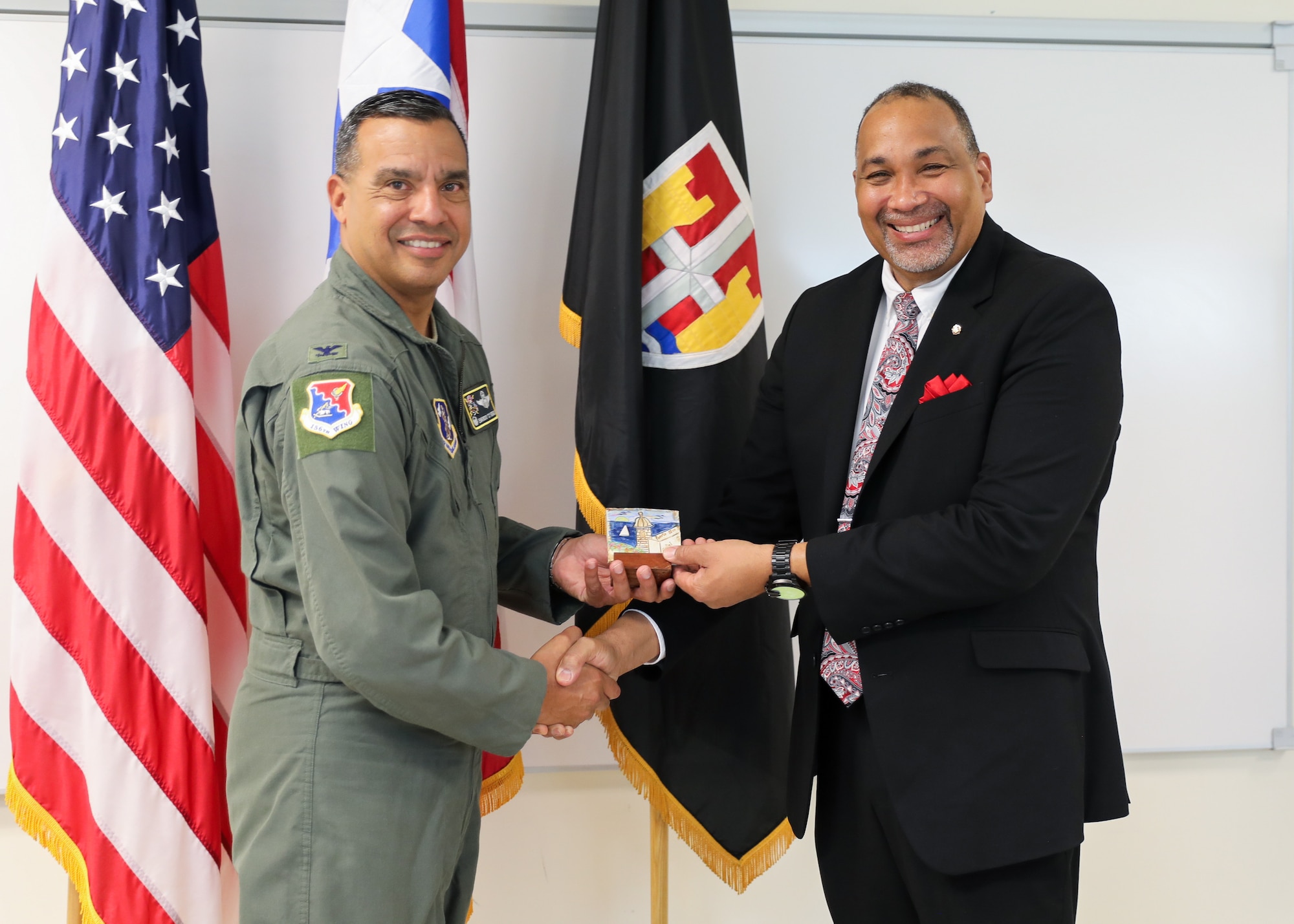 U.S. Air Force Col. Evaristo Orengo, the 156th Wing commander, Puerto Rico Air National Guard, delivers a souvenir to David O. Andino-Aquino, director of protocol, with the National Guard Bureau protocol office, after completing a three-day joint protocol training at Fort Buchanan, Bayamón, Puerto Rico, Feb. 27, 2025. More than 53 participants received 20 hours of classroom instruction, multiple scenario-based training exercises, and professional anecdotes covering several topics, including military and civilian distinguished visitor protocol, key leadership engagement management, military precedence rules, drafting invitations, the science of seating plans, flag protocol, budgeting, and protocol funding. (U.S. National Guard photo by Mr. Alexis Vélez)
