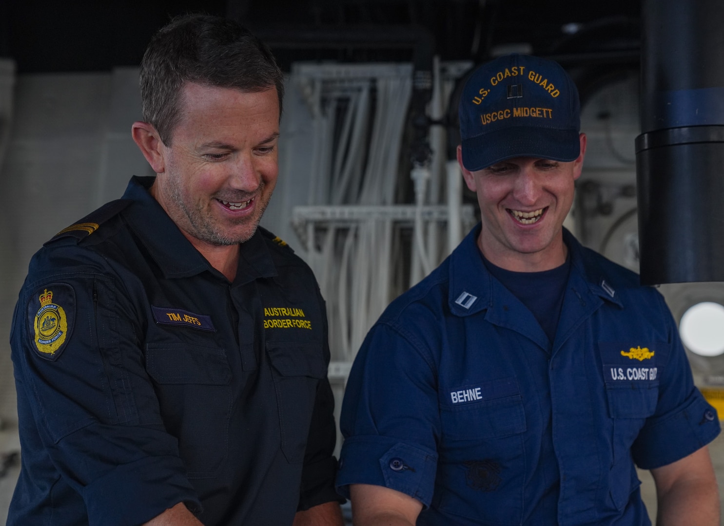 Lt. Jacob Behne, the combat systems officer on Coast Guard Cutter Midgett (WMSL 757) and Senior Border Force Officer Tim Jeffs with the Australian Border Force discuss similarities between the organizations on the bridge of the Midgett on Feb. 28, 2025. Behne previously deployed to Jeffs’ unit in the Torres Strait as an observer as part of the Coast Guard and Australian Border Force’s Memorandum of Agreement. Presence and collaborative interaction between the United States and Australia strengthen the safety and security of all countries, fostering a committed, durable network of maritime partners with shared principles and norms. (U.S. Coast Guard photo by Petty Officer 3rd Class Jennifer Nilson)