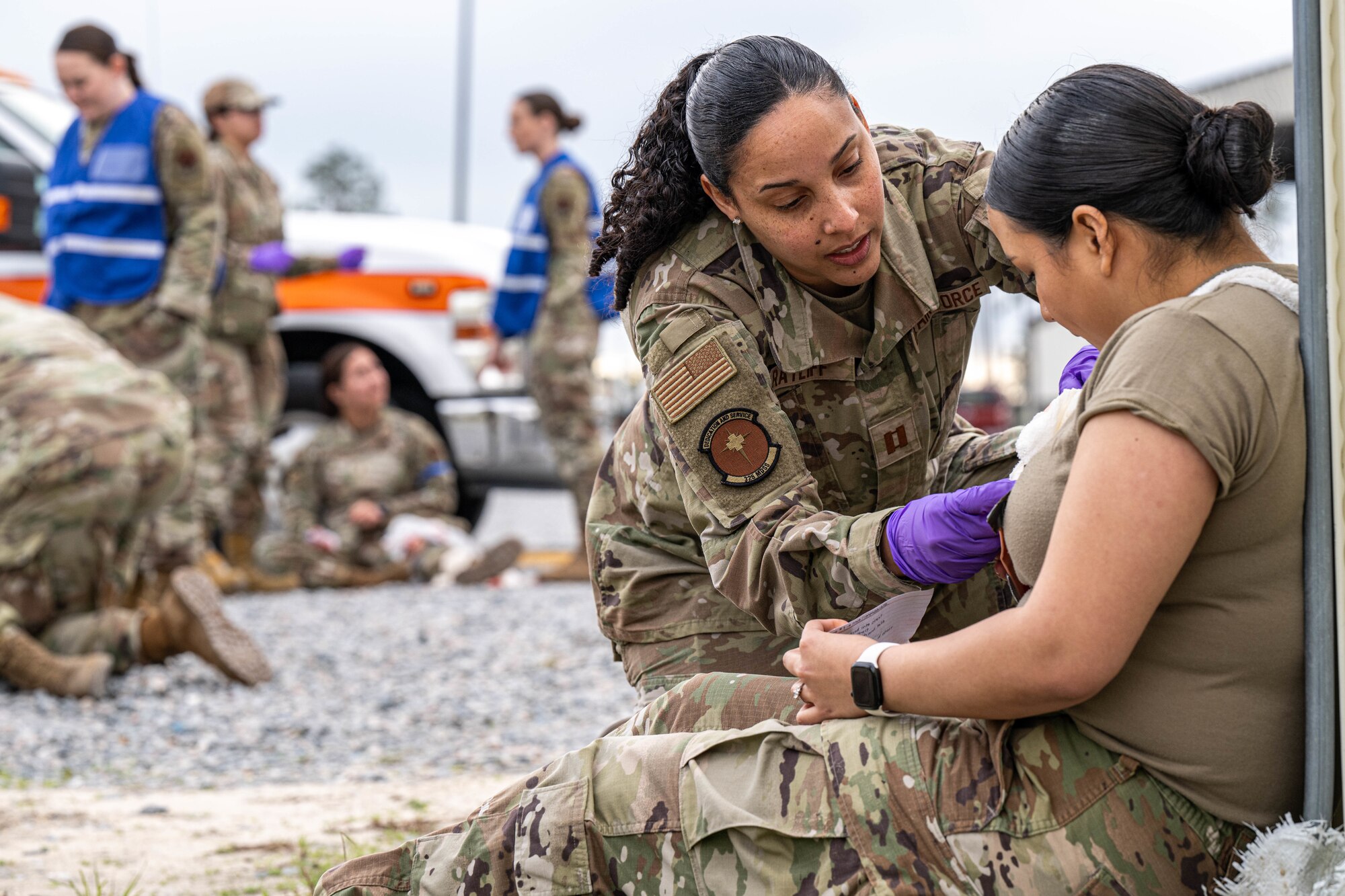 A person attends/treats someone on the ground during a medical exercise.