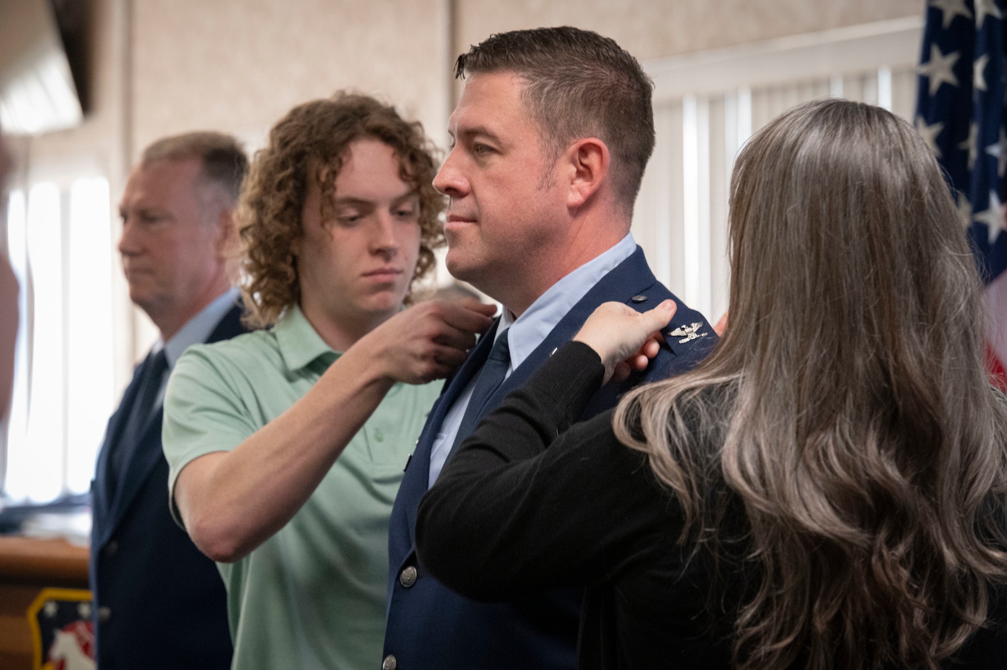a young man and woman pin rank on a man in uniform