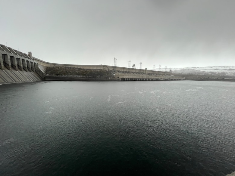 Rain clouds hover over a river and dam