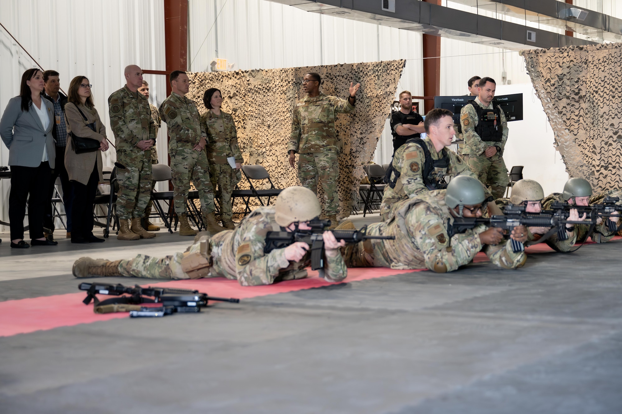 U.S. Air Force Airmen attending the U.S. Air Force Expeditionary Operations School Ready Airmen Training, scan for targets during a shooting simulation at gunfighter gymnasium on Joint Base McGuire-Dix-Lakehurst, N.J., Feb. 26, 2025. Gen. Johnny Lamontagne, commander of Air Mobility Command, and Chief Master Sgt. Jamie Newman, AMC command chief, visited JB MDL and underscored AMC’s initiatives centered on developing Mission Ready Airmen, enhancing operational capabilities and strengthening relationships across the military community. (U.S. Air Force photo by Capt. Braxton Williams)