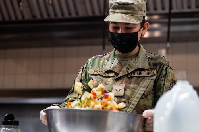 Airman shakes a large bowl of ingredients to combine them