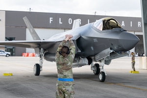 An aircraft maintainer marshals in a F-35A Lightning II aircraft during its arrival.