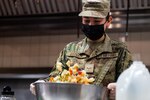 Airman shakes a large bowl of ingredients to combine them