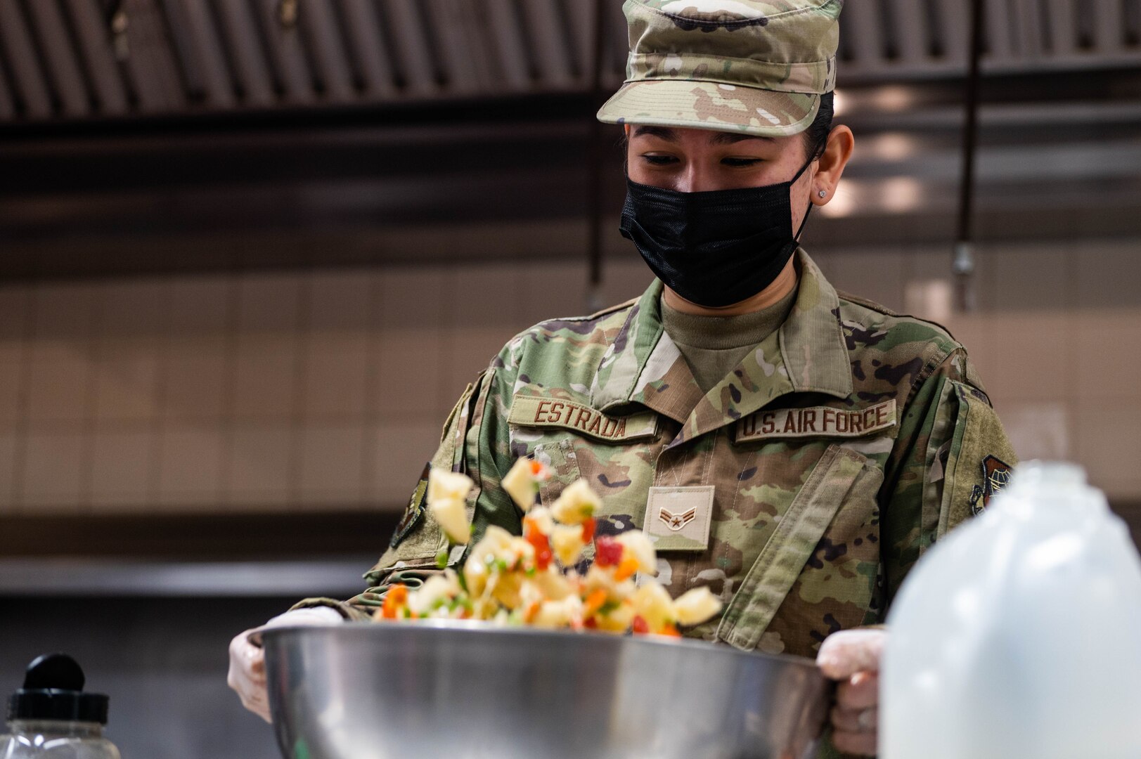 Airman shakes a large bowl of ingredients to combine them