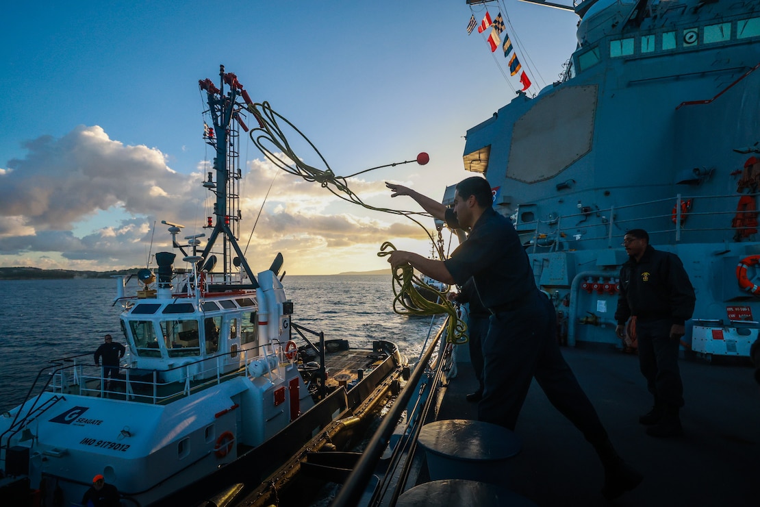 Operations Specialist 3rd Class Kevin Figueroa-Rodrigues throws a heaving line to the tug boat during a Sea and Anchor evolution aboard the Arleigh Burke-class guided-missile destroyer USS Bulkeley (DDG 84), as the ship arrives to Souda Bay, Greece, Nov. 18, 2024.