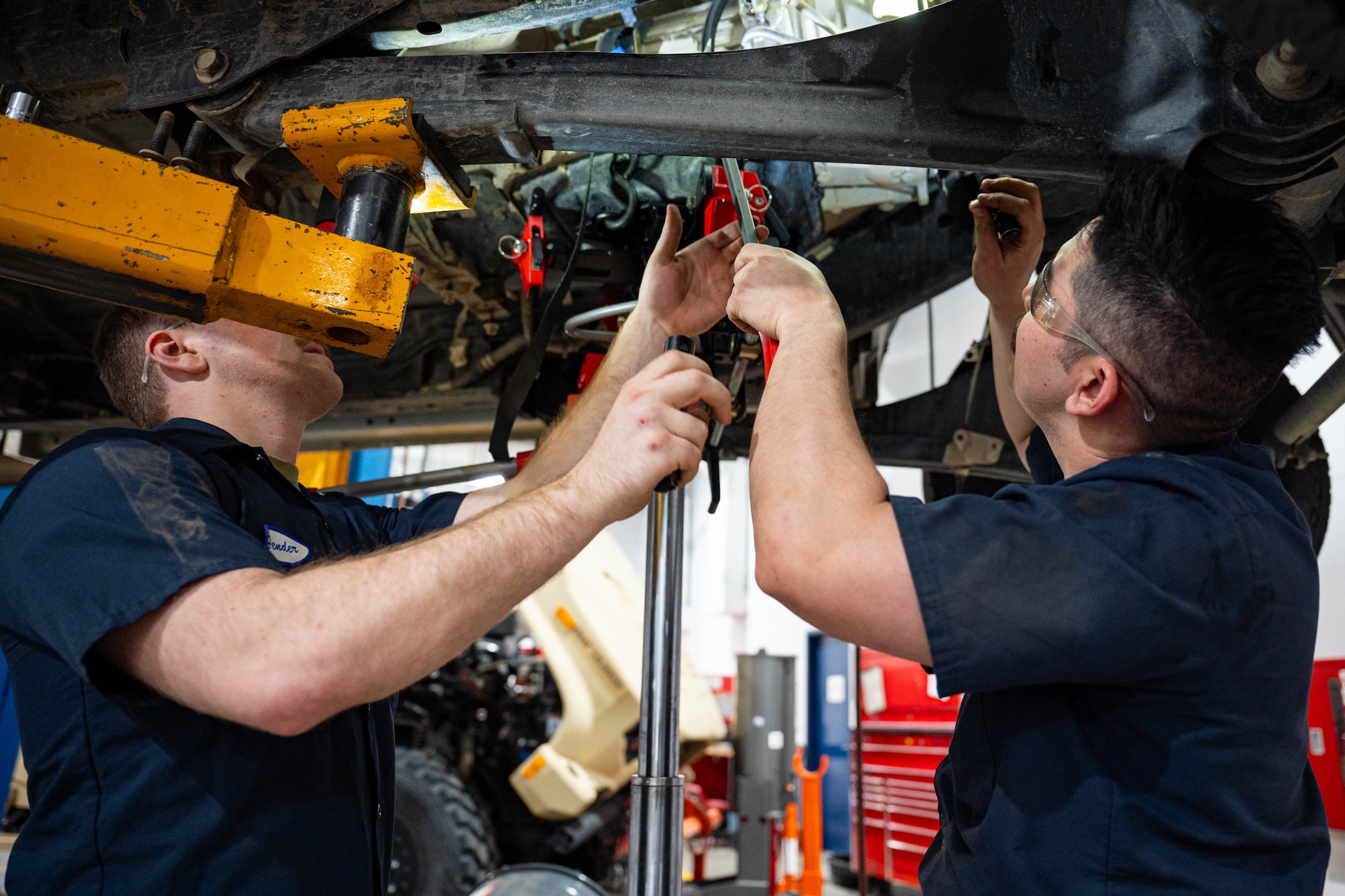 Mechanics perform maintenance on a vehicle.