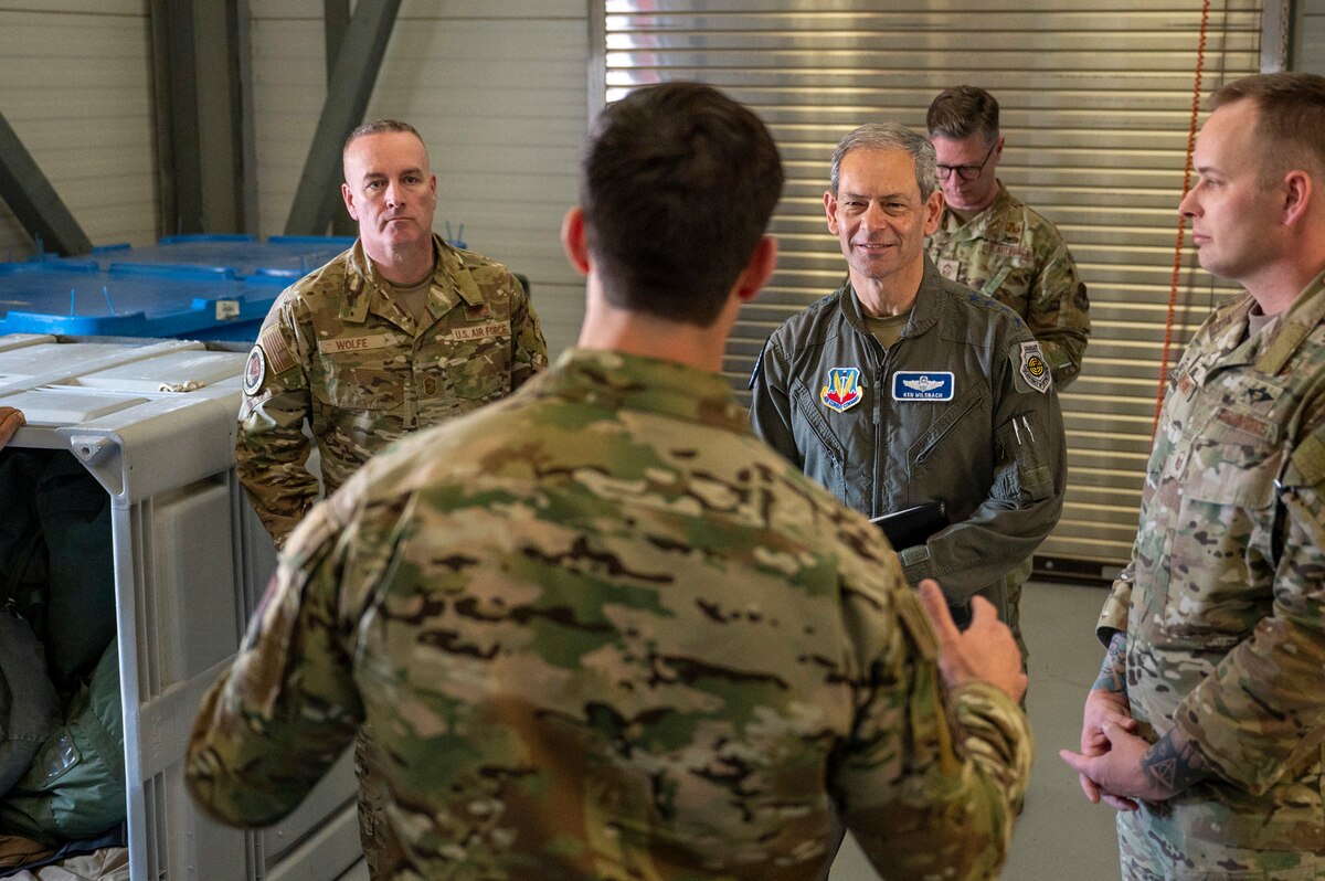 U.S. Air Force Gen. Ken Wilsbach, commander of Air Combat Command, right, and Chief Master Sgt. Dave Wolfe, ACC command chief, left, listen to a brief from a 68th Rescue Squadron Airman at Davis-Monthan Air Force Base, Arizona, Feb. 28, 2025. Wilsbach and Wolfe traveled around the base and met with leadership to discuss the squadrons’ needs. (U.S. Air Force photo by Senior Airman Devlin Bishop)