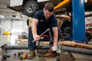 A mechanic uses tools to fix a vehicle.