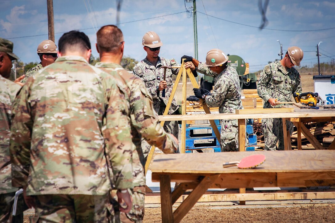 Sailors wearing protective gear work at a construction site.