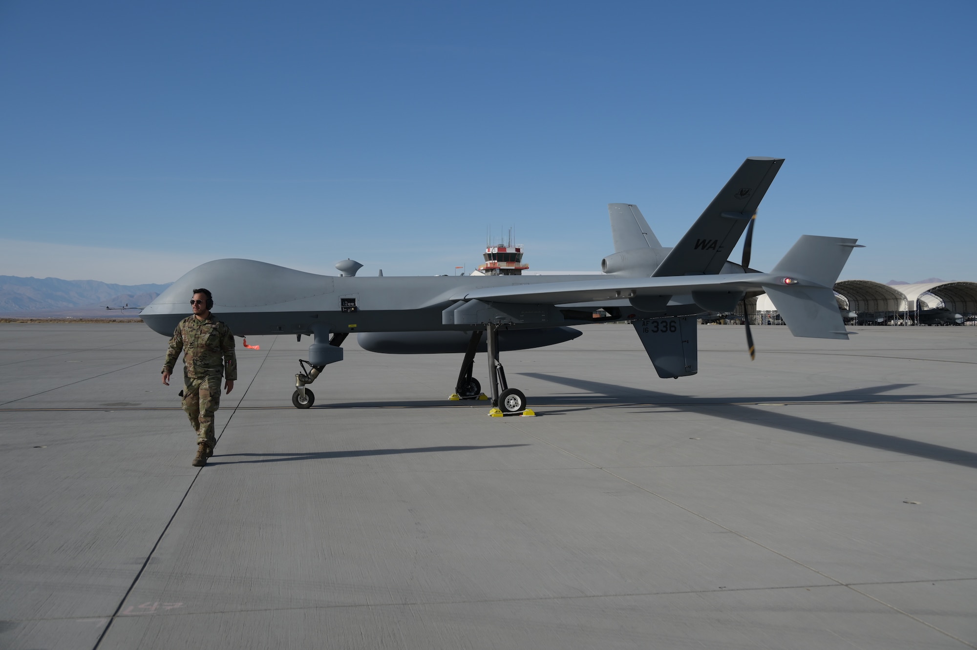 A man in a military uniform walks away from a remotely piloted aircraft.