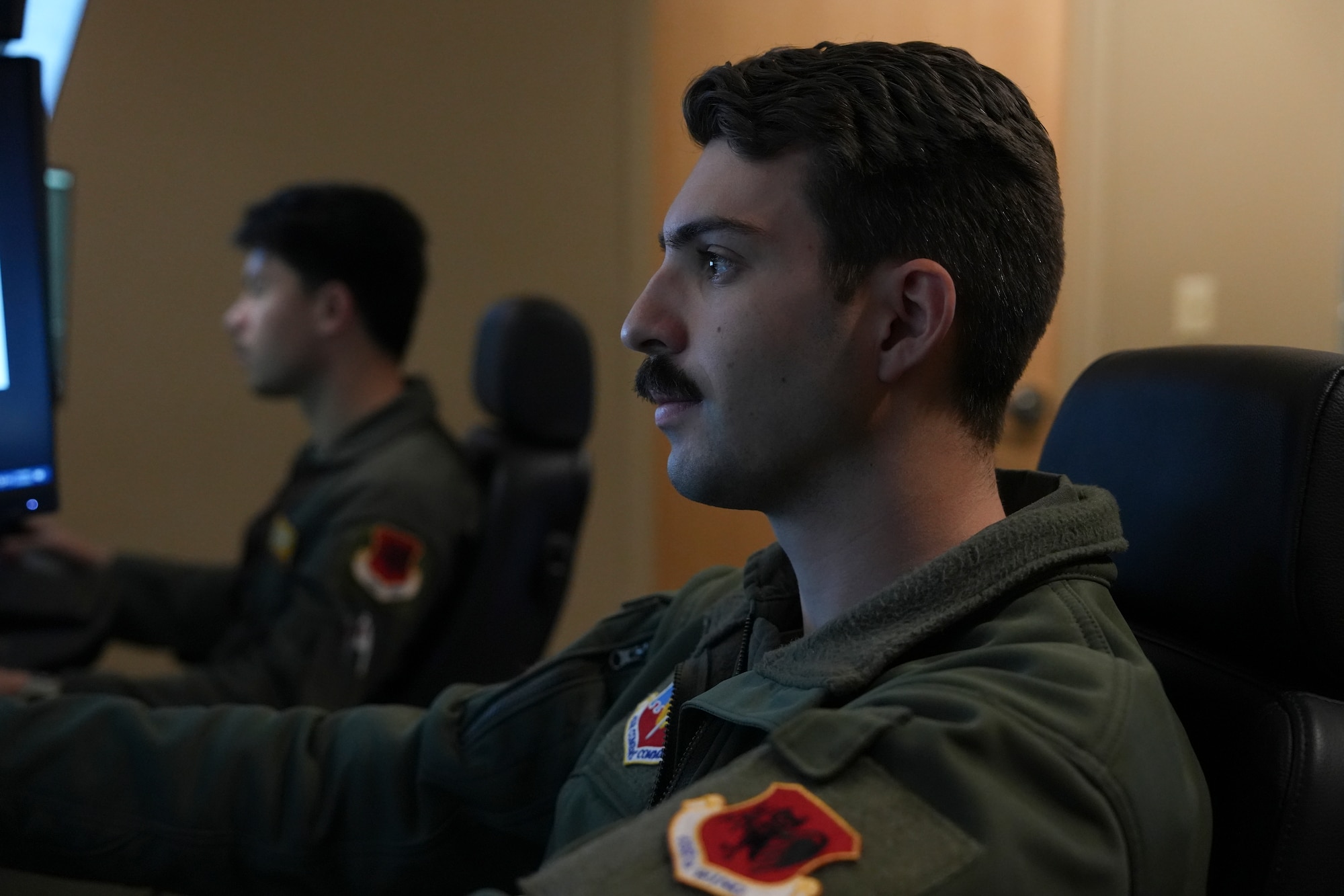 A man in a military uniform operates a flight simulator.