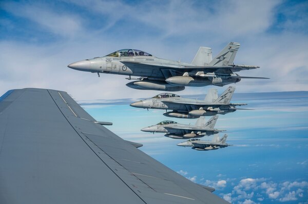Four fighter jets fly in a partly cloudy sky.